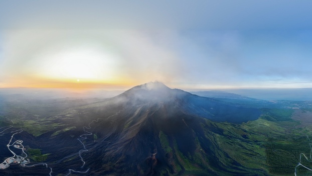 Aerial view of Mount Etna with steam rising from the crater and winding roads on the volcanic slopes at sunset Castiglione di Sicilia Sicily Italy. Aerial view of Mount Etna with steam rising from the crater and winding roads on the volcanic slopes at sunset Castiglione di Sicilia Sicily Italy.