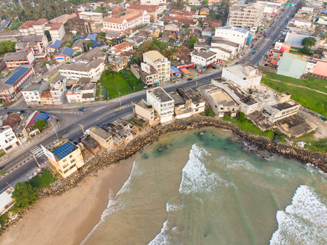 Aerial view of urban buildings and a coastal road with waves breaking on the shore in Galle Southern Province Sri Lanka.