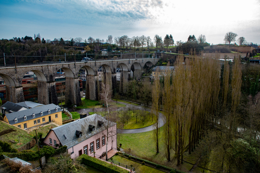 Aerial view of the historic stone arches of the Passerelle viaduct spanning over a lush park with trees and traditional buildings in Luxembourg Luxembourg Luxembourg.