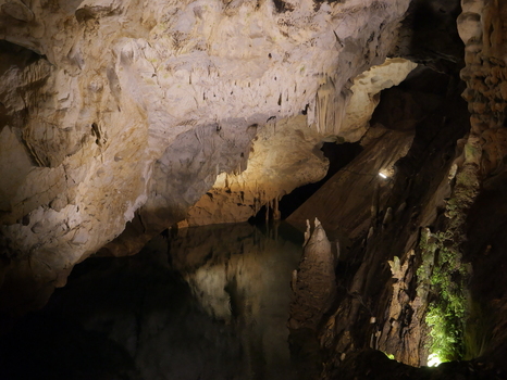View of Vrelo Cave featuring intricate stalactites and stalagmites reflecting in a dark underground pool in Matka Komuna e Sopishtes North Macedonia.