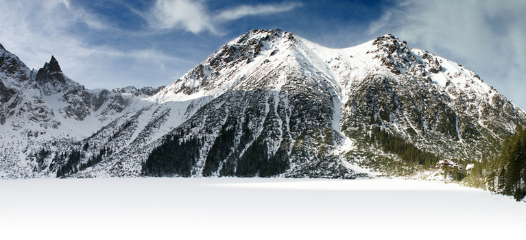 View of the frozen Morskie Oko lake covered in white snow and surrounded by the jagged granite peaks of the Tatra Mountains under a blue sky Tatra County Lesser Poland Poland. View of the frozen Morskie Oko lake covered in white snow and surrounded by the jagged granite peaks of the Tatra Mountains under a blue sky Tatra County Lesser Poland Poland.