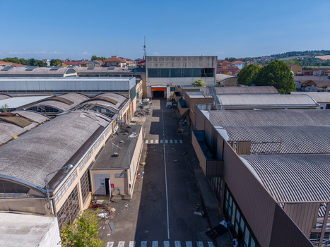Aerial view of the industrial complex featuring large warehouses with corrugated metal roofs and a central access road in Casale Monferrato Piedmont Italy. Aerial view of the industrial complex featuring large warehouses with corrugated metal roofs and a central access road in Casale Monferrato Piedmont Italy.