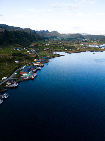 Aerial view of the coastal village of Tangstad featuring colorful houses and fishing boats along the deep blue fjord under a soft sky Leknes Nordland Norway. Aerial view of the coastal village of Tangstad featuring colorful houses and fishing boats along the deep blue fjord under a soft sky Leknes Nordland Norway.