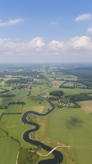 Aerial view of the winding Berkel river flowing through the lush green meadows and agricultural fields of the Dutch countryside in Almen Gelderland Netherlands. Aerial view of the winding Berkel river flowing through the lush green meadows and agricultural fields of the Dutch countryside in Almen Gelderland Netherlands.
