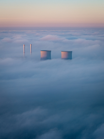 Aerial view of RWE Clauscentrale power plant cooling towers and chimneys rising above a dense layer of fog under a pastel sky in Maasbracht Limburg Netherlands. Aerial view of RWE Clauscentrale power plant cooling towers and chimneys rising above a dense layer of fog under a pastel sky in Maasbracht Limburg Netherlands.