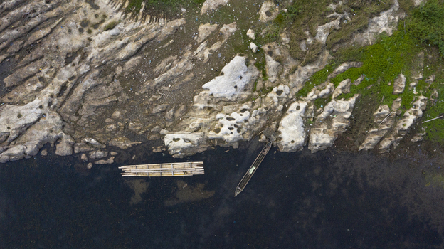 Danau Kerinci Jambi Indonesia 25 September 2026 Aerial view of the rocky shoreline of Danau Kerinci with a traditional wooden boat and a bamboo raft floating in the dark water. Danau Kerinci Jambi Indonesia 25 September 2026 Aerial view of the rocky shoreline of Danau Kerinci with a traditional wooden boat and a bamboo raft floating in the dark water.