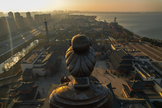 Aerial view of Huayi Brother Film World featuring traditional Chinese architecture and a large statue overlooking the park at sunset in Suzhou Jiangsu China. Aerial view of Huayi Brother Film World featuring traditional Chinese architecture and a large statue overlooking the park at sunset in Suzhou Jiangsu China.