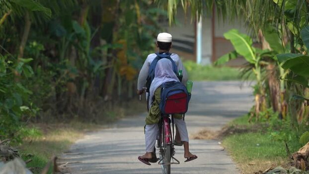 View of a man and child on a bicycle in rural Bogura Bangladesh.