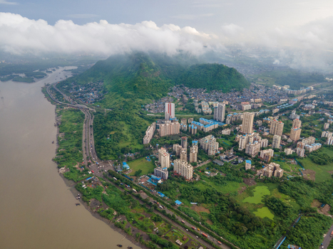 Aerial view of modern high rise residential buildings nestled between lush green hills and a wide river in Thane Maharashtra India. Aerial view of modern high rise residential buildings nestled between lush green hills and a wide river in Thane Maharashtra India.