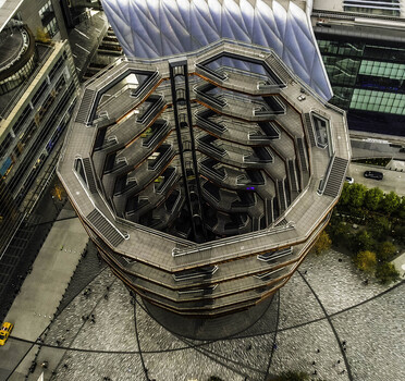 Aerial view of The Vessel at Hudson Yards a copper colored honeycomb like structure with interconnected staircases surrounded by modern skyscrapers and urban plazas in New York New York United States.