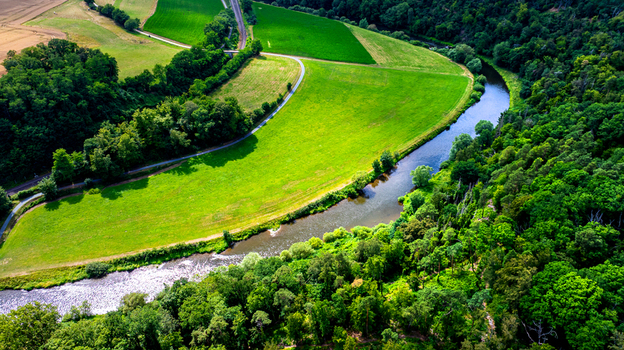 Aerial view of the Lahn river winding through lush green meadows and dense forests in Germany.