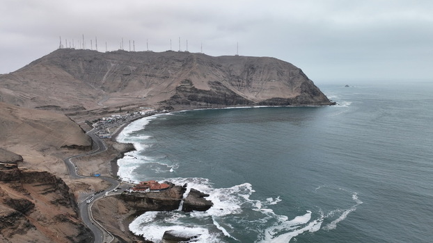 Aerial view of the rugged coastline and cliffs of the Morro Solar area with a winding coastal road and the Pacific Ocean waves crashing against the shore in Barranco Lima Province Peru.