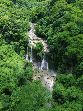 Aerial view of the waterfall in Sitakund surrounded by dense green forest with people swimming in the natural pool at the base in Sitakund Chittagong Division Bangladesh. Aerial view of the waterfall in Sitakund surrounded by dense green forest with people swimming in the natural pool at the base in Sitakund Chittagong Division Bangladesh.