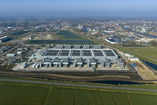 Aerial view of the Google data center with solar panels and surrounding green fields under a clear blue sky in Winschoten Groningen Netherlands.
