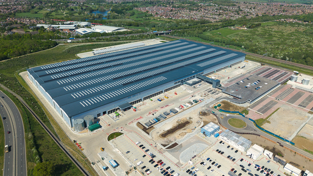 Aerial view of Symmetry Park logistics center featuring a massive warehouse with solar panels and extensive parking facilities in Kettering England United Kingdom. Aerial view of Symmetry Park logistics center featuring a massive warehouse with solar panels and extensive parking facilities in Kettering England United Kingdom.
