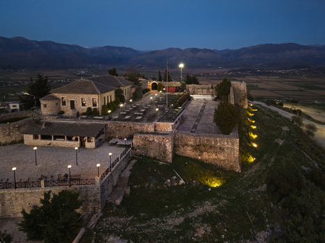 Aerial view of Lekuresi Castle at twilight featuring stone walls illuminated courtyards and surrounding hills in Saranda Vlore County Albania. Aerial view of Lekuresi Castle at twilight featuring stone walls illuminated courtyards and surrounding hills in Saranda Vlore County Albania.