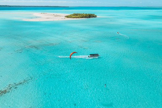 Aerial view of Aitutaki lagoon with a kitesurfer a boat and a small tropical island surrounded by turquoise water in Cook Islands. Aerial view of Aitutaki lagoon with a kitesurfer a boat and a small tropical island surrounded by turquoise water in Cook Islands.