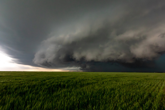View of a dramatic supercell storm cloud looming over a vast green field in Oklahoma City Oklahoma United States.