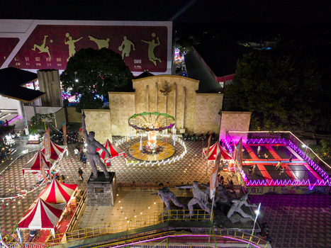 Aerial view of GOR Gelarsena Klaten Night Market with a glowing carousel trampolines and striped tents at night in Kecamatan Klaten Utara Jawa Tengah Indonesia. Aerial view of GOR Gelarsena Klaten Night Market with a glowing carousel trampolines and striped tents at night in Kecamatan Klaten Utara Jawa Tengah Indonesia.