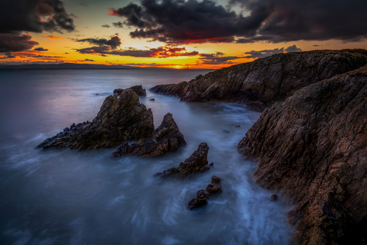 View of jagged rocks and rugged cliffs at Howth under a dramatic sunset sky with dark clouds Ireland. View of jagged rocks and rugged cliffs at Howth under a dramatic sunset sky with dark clouds Ireland.