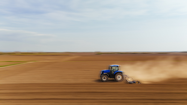 Aerial view of a lone tractor carving furrows in the rich brown earth under a vast pale sky Vojvodina plain Sremska Mitrovica Vojvodina Serbia. Aerial view of a lone tractor carving furrows in the rich brown earth under a vast pale sky Vojvodina plain Sremska Mitrovica Vojvodina Serbia.