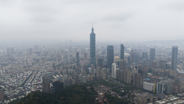 Aerial view of the iconic Taipei 101 skyscraper rising above the dense urban skyline and residential buildings under a misty sky Taipei Taiwan.