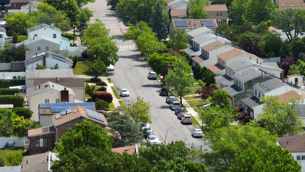 Aerial view of a quiet residential street lined with houses featuring solar panels and lush green trees near the Staten Island Greenbelt in New York New York United States.