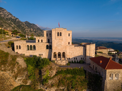 Aerial view of the historic Kruje Castle with its stone fortifications and red flag set against rugged mountains in Kruje Durres County Albania.