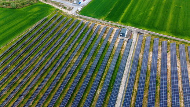 Aerial view of a solar farm with rows of photovoltaic panels and green agricultural fields in Sabac Vojvodina Serbia.