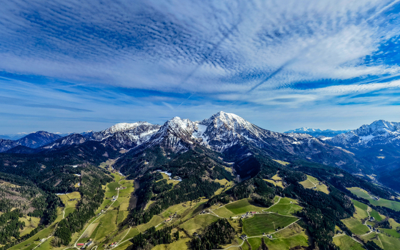 Aerial view of snow capped peaks rise majestically over the lush green Windischgarsten valley under a bright blue sky Windischgarsten Upper Austria Austria. Aerial view of snow capped peaks rise majestically over the lush green Windischgarsten valley under a bright blue sky Windischgarsten Upper Austria Austria.