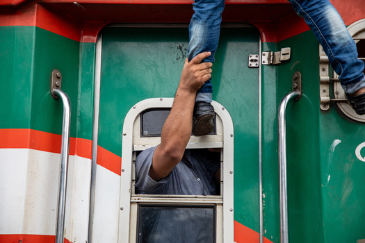 Dhaka Bangladesh 15 June 2018 View of a man helping a passenger climb into a train through a window at Airport Railway Station during the Eid al Fitr rush. Dhaka Bangladesh 15 June 2018 View of a man helping a passenger climb into a train through a window at Airport Railway Station during the Eid al Fitr rush.