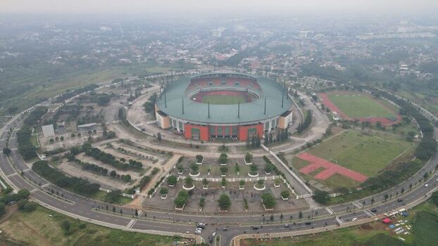 Aerial view of Pakansari Stadium surrounded by parking lots green fields and urban infrastructure in Kecamatan Cibinong Jawa Barat Indonesia. Aerial view of Pakansari Stadium surrounded by parking lots green fields and urban infrastructure in Kecamatan Cibinong Jawa Barat Indonesia.
