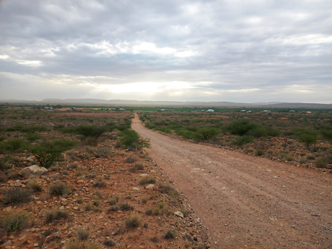 View of a dirt road stretching through the arid landscape of Anysberg Nature Reserve featuring sparse shrubs rocky terrain and distant mountains in Anysberg Western Cape South Africa. View of a dirt road stretching through the arid landscape of Anysberg Nature Reserve featuring sparse shrubs rocky terrain and distant mountains in Anysberg Western Cape South Africa.