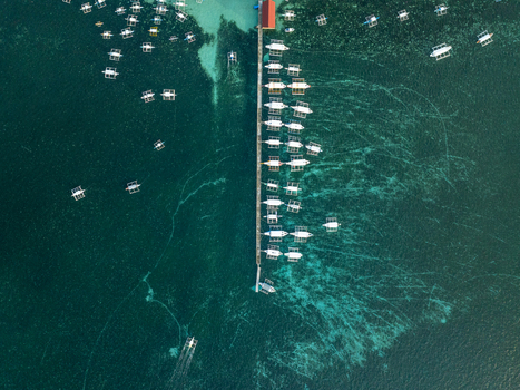 Aerial view of Naked Island surrounded by turquoise waters with numerous traditional outrigger boats docked at a long wooden pier Siargao Philippines. Aerial view of Naked Island surrounded by turquoise waters with numerous traditional outrigger boats docked at a long wooden pier Siargao Philippines.