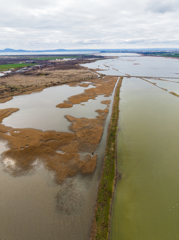 Aerial view of Lake Atanasovsko featuring salt pans dry reeds and a narrow dyke under a cloudy sky in Burgas Burgas Bulgaria. Aerial view of Lake Atanasovsko featuring salt pans dry reeds and a narrow dyke under a cloudy sky in Burgas Burgas Bulgaria.