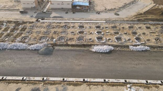 Aerial view of the Pantai Indah Kapuk 2 construction site featuring rows of rectangular burial pits in the dirt ground adjacent to paved roads in Kecamatan Penjaringan Banten Indonesia. Aerial view of the Pantai Indah Kapuk 2 construction site featuring rows of rectangular burial pits in the dirt ground adjacent to paved roads in Kecamatan Penjaringan Banten Indonesia.
