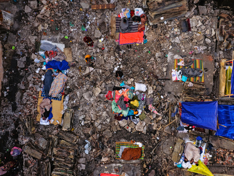 Aerial view of Korail Basti showing people resting on mats amidst rubble and makeshift shelters with colorful blankets and blue tarps in Dhaka Dhaka Division Bangladesh.