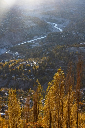 View of the Hunza Valley with golden autumn trees a winding river and mountain slopes in Karimabad GB Pakistan. View of the Hunza Valley with golden autumn trees a winding river and mountain slopes in Karimabad GB Pakistan.