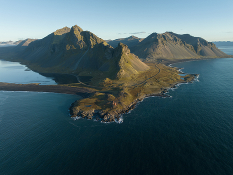Aerial view of rugged mountains meeting the deep blue sea at the Stokksnes Peninsula where light dances on the dark sand and rocky shores Hvalnes Iceland. Aerial view of rugged mountains meeting the deep blue sea at the Stokksnes Peninsula where light dances on the dark sand and rocky shores Hvalnes Iceland.
