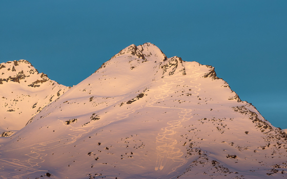 Aerial view of snow covered mountain peaks glow under the pastel blush of dawn the trails etched into the landscape Val Thorens Auvergne Rh&ocirc;ne Alpes France.