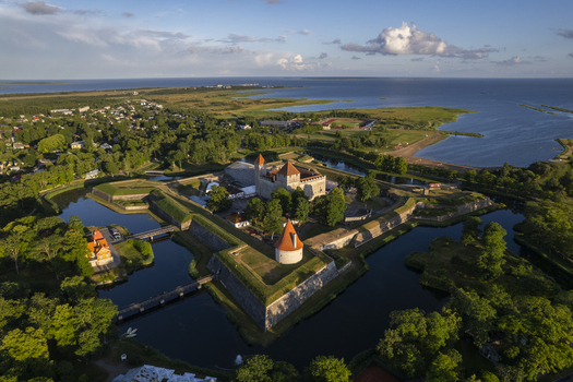 Aerial view of Kuressaare Castle surrounded by a moat and lush green trees with the town and coastline in the background Kuressaare Saare County Estonia.