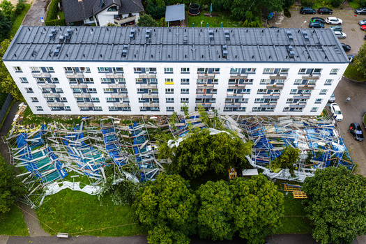 Riga Latvia 23 August 2026 Aerial view of a collapsed scaffolding structure lying on the ground next to a multi story apartment building in a residential area.