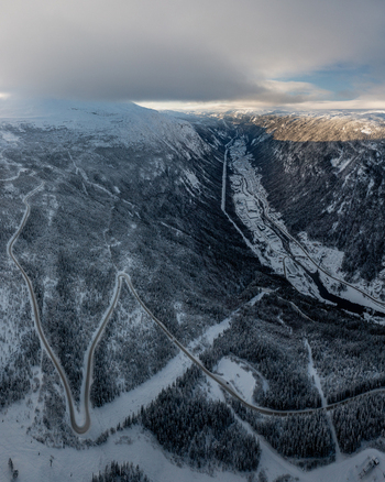 Aerial view of the winding road leading through the snow covered mountain valley near Gaustablikk Fjellresort in Rjukan Telemark Norway. Aerial view of the winding road leading through the snow covered mountain valley near Gaustablikk Fjellresort in Rjukan Telemark Norway.