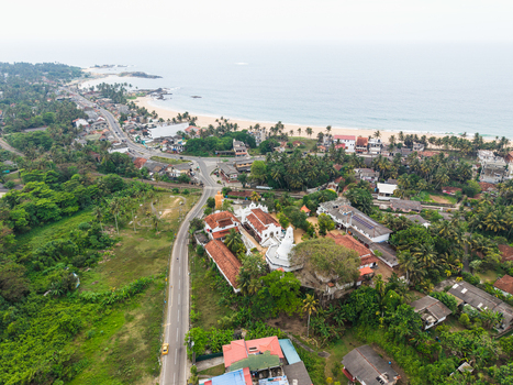 Aerial view of Kumarakanda Kumara Maha Viharaya temple complex with its white stupa and traditional architecture near the coastline and sandy beach Hikkaduwa Southern Province Sri Lanka. Aerial view of Kumarakanda Kumara Maha Viharaya temple complex with its white stupa and traditional architecture near the coastline and sandy beach Hikkaduwa Southern Province Sri Lanka.