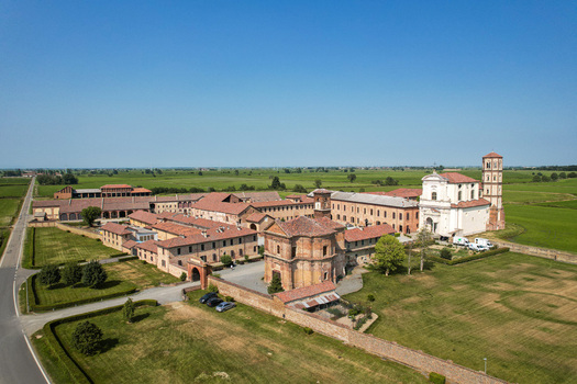 Aerial view of Abbazia di Lucedio surrounded by historic brick buildings lush green fields and clear blue sky in Trino Piemonte Italy. Aerial view of Abbazia di Lucedio surrounded by historic brick buildings lush green fields and clear blue sky in Trino Piemonte Italy.