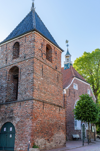 View of the historic Greetsieler Kirche brick church and its separate bell tower under a clear blue sky in Krummhorn Lower Saxony Germany. View of the historic Greetsieler Kirche brick church and its separate bell tower under a clear blue sky in Krummhorn Lower Saxony Germany.