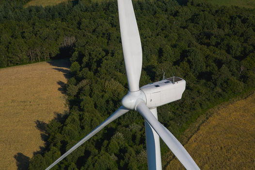 Aerial view of a towering wind turbine gracefully contrasts against the backdrop of a dense verdant forest embodying sustainable energy Salles Curan Occitanie France. Aerial view of a towering wind turbine gracefully contrasts against the backdrop of a dense verdant forest embodying sustainable energy Salles Curan Occitanie France.