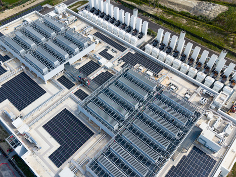 Aerial view of a modern data center campus featuring rows of cooling units and solar panels on the roof in Melegnano Lombardy Italy.