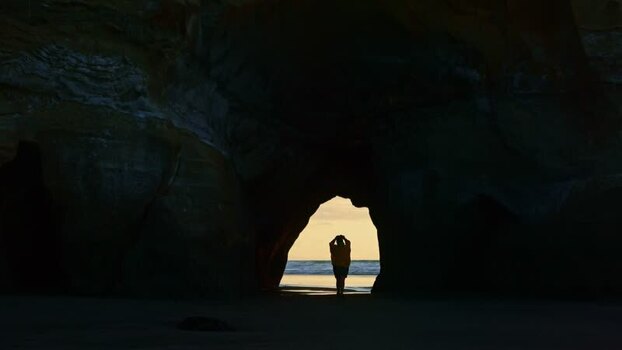 View of a person framed by a sea cave entrance New Zealand. View of a person framed by a sea cave entrance New Zealand.
