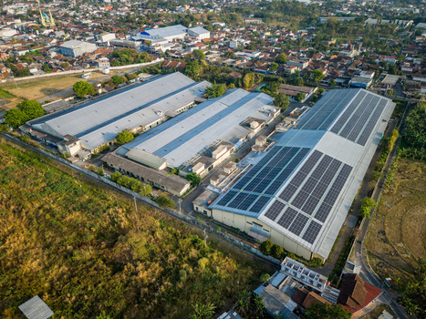 Aerial view of large industrial facility featuring extensive rooftop solar panel arrays surrounded by urban development and greenery in Semarang Regency Central Java Indonesia. Aerial view of large industrial facility featuring extensive rooftop solar panel arrays surrounded by urban development and greenery in Semarang Regency Central Java Indonesia.